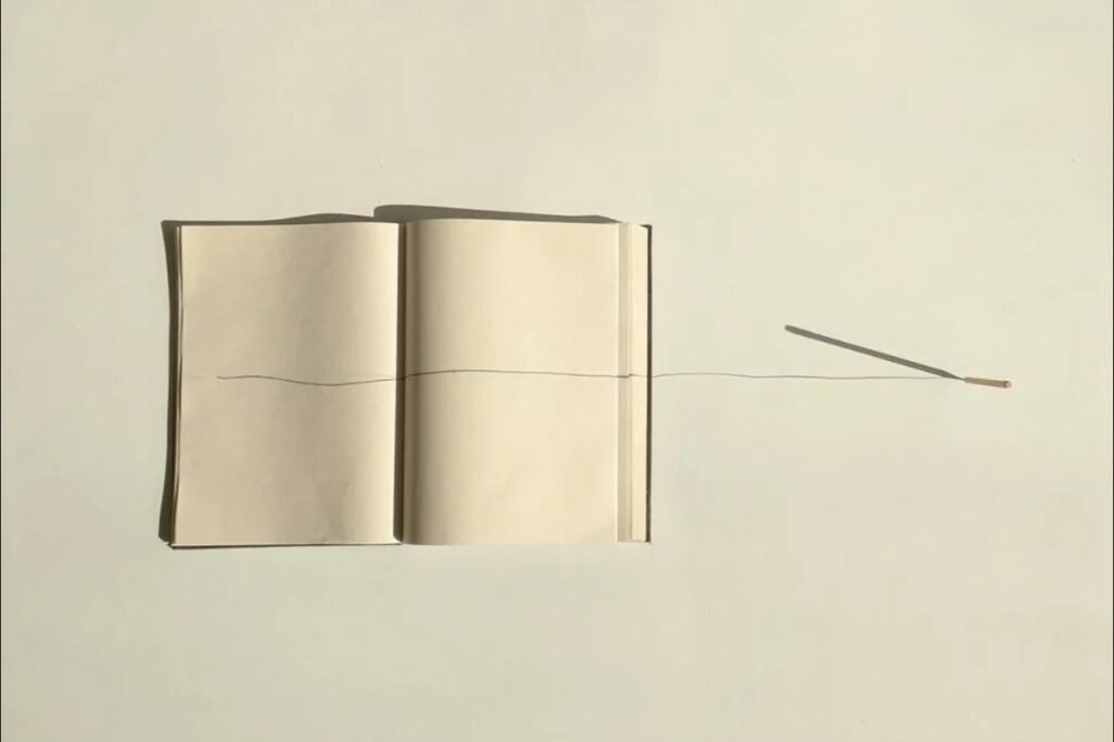 Suspensiones de la memoria (2017), libro abierto con un trazo de lápiz que sale de sus páginas, Jorge Ocampo Rendón y Juan Esteban Ocampo Rendón.